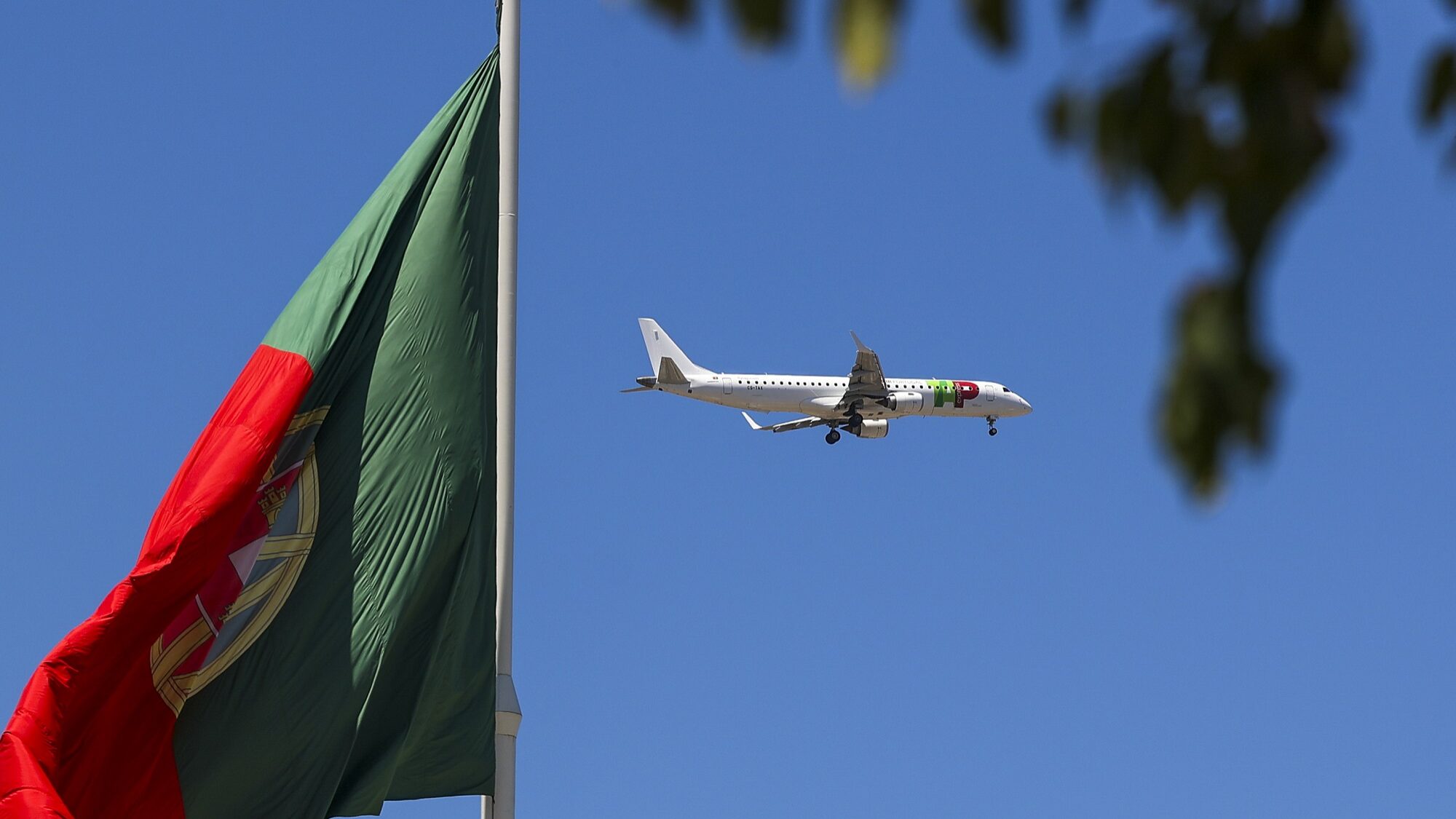 Um avião da TAP voa sobre uma bandeira de Portugal, no Parque Eduardo VII, em Lisboa, 10 de julho de 2023. JOSÉ SENA GOULÃO/LUSA